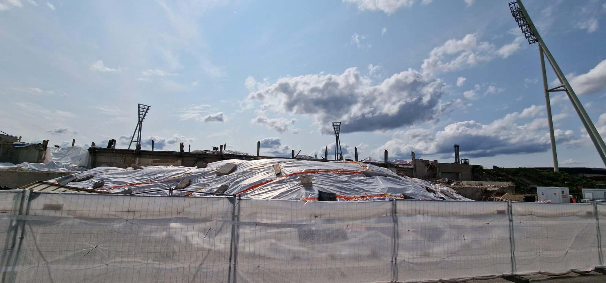 Der mit weißen Planen abgedeckte Bauschuttberg am Jahnsportpark hinter einem Bauzaun
